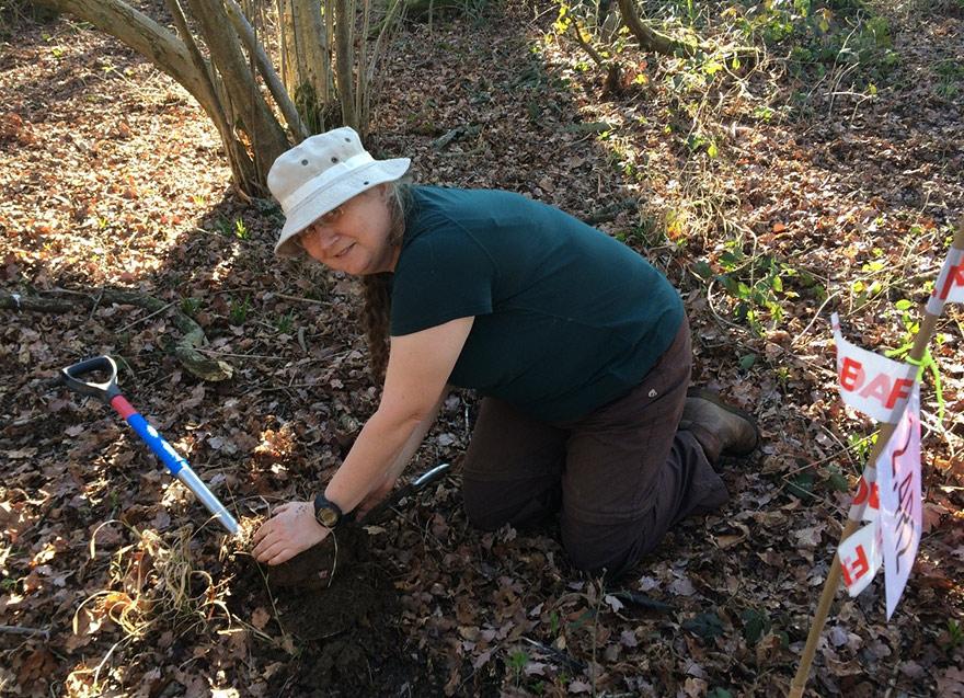 Woman digging in leaf litter under tree