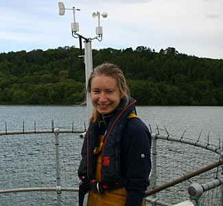 Dr Ellie Mackay working on a lake monitoring buoy, photo by Jessica Richardson Woman standing by a lake