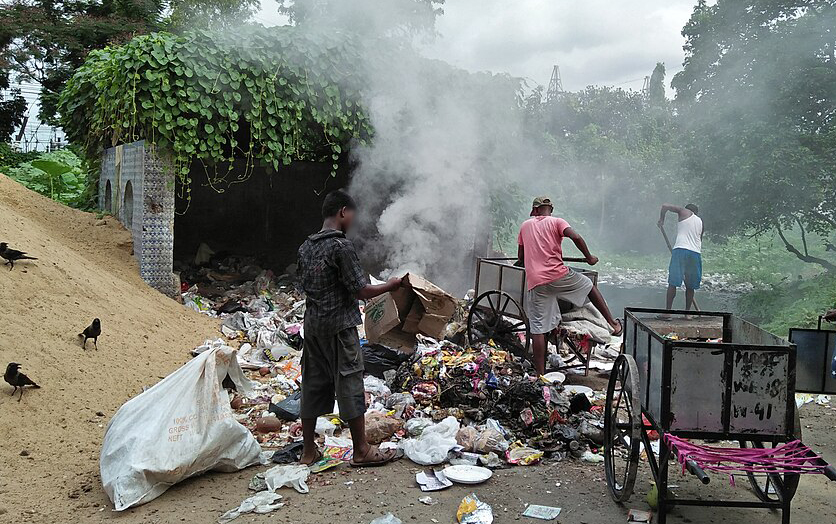 Three people tending to burning garbage on a roadside. Image: Biswarup Ganguly (CC-BY-SA 4.0)
