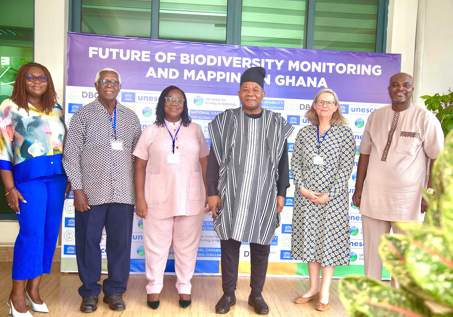Six people stand in front of a poster called future of biodiversity monitoring and mapping in Ghana