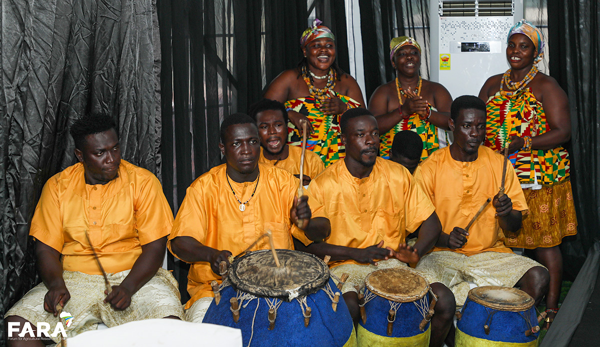 3 people standing behind 5 people sitting playing drums