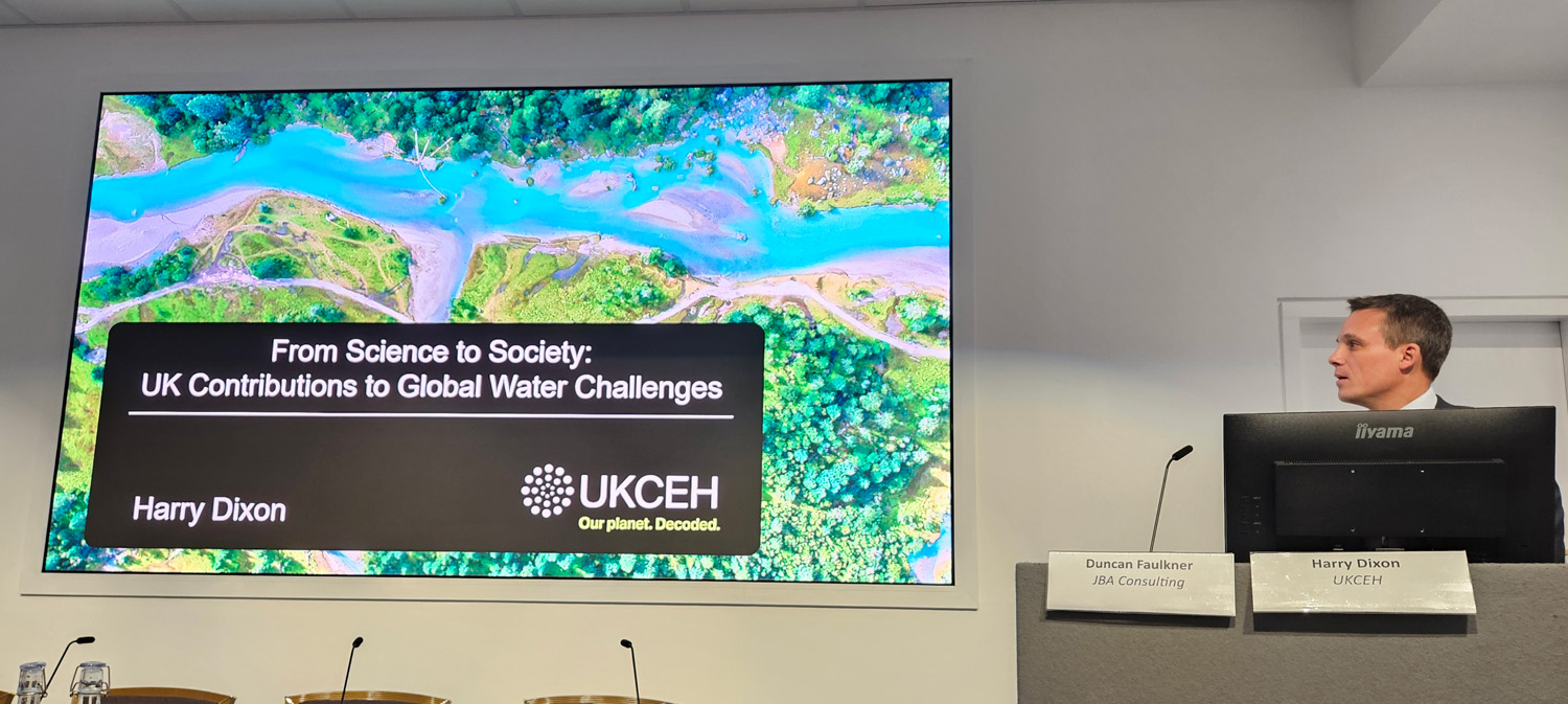 Prof Harry Dixon at a lectern beside a large presentation screen