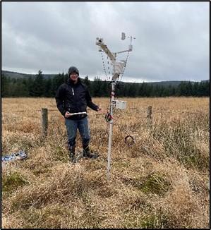 Person standing next to a weather station in a field