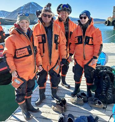 Three BIOPOLE scientists and poet laureate Simon Armitage on a pier in the Arctic