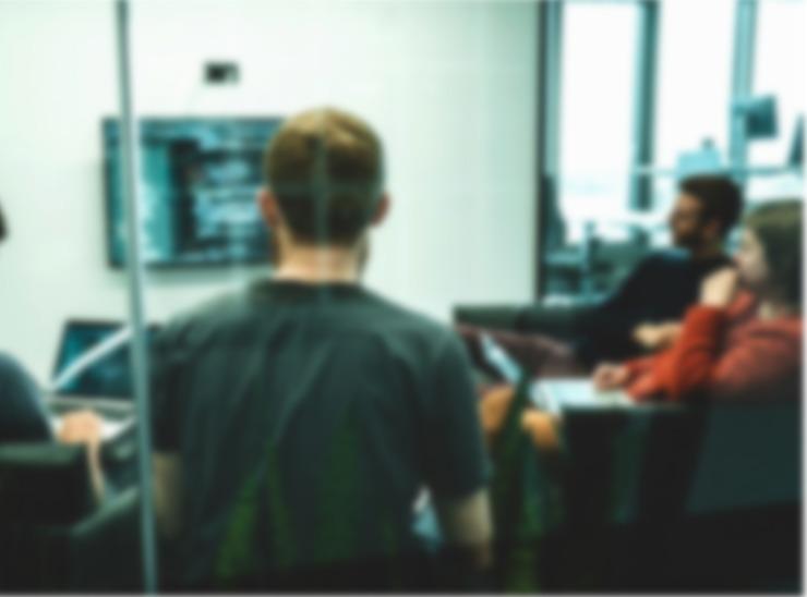 Group of people in a meeting room looking at a screen on a wall