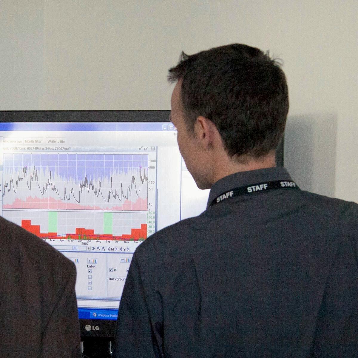 Back of a person looking at a computer beside another person mostly out of shot