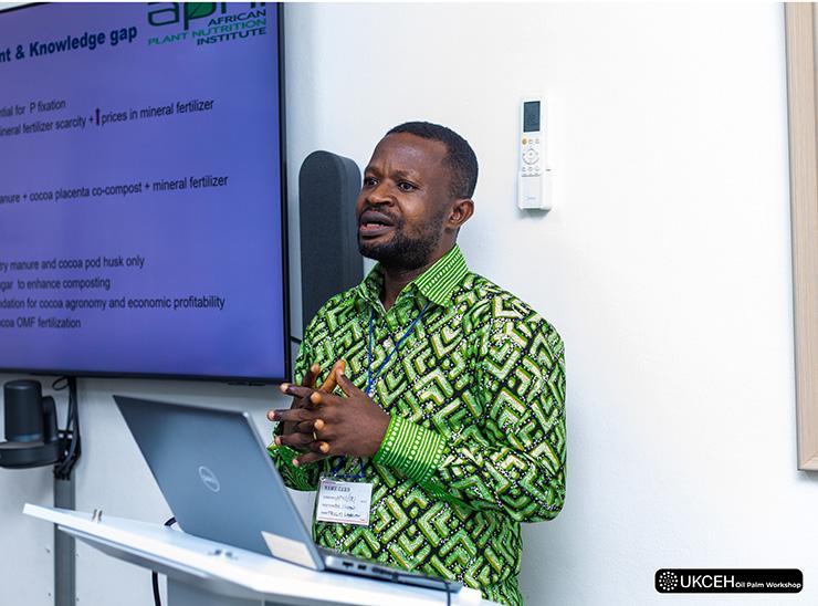 Presenter stands at lectern beside large screen