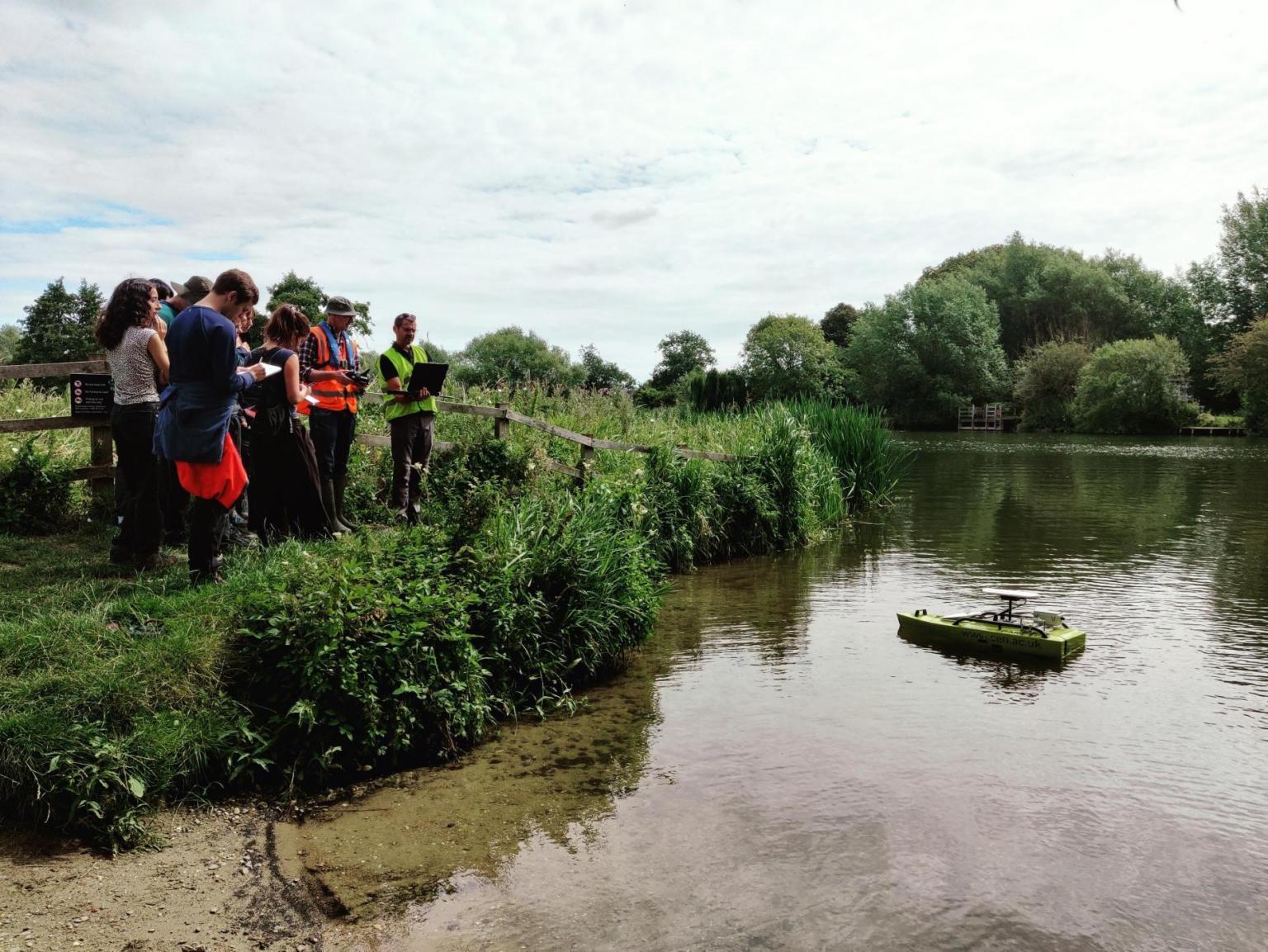 Group of people on river bank with a small boat on the river