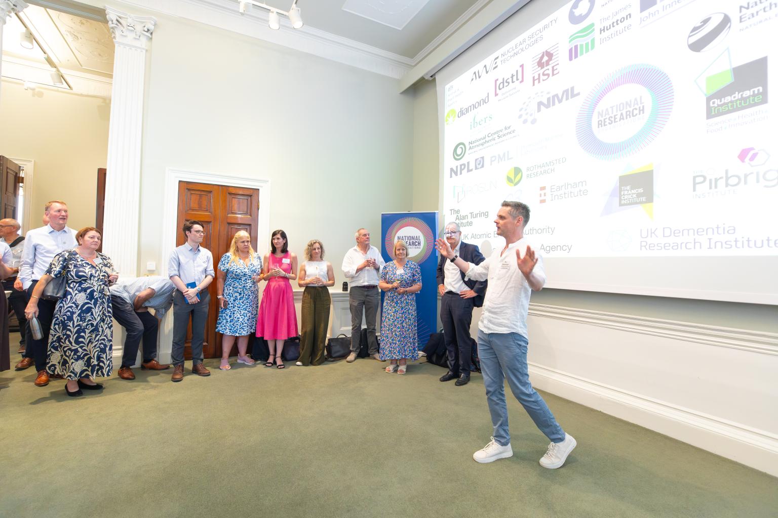 Man talking in front of a screen and group of people