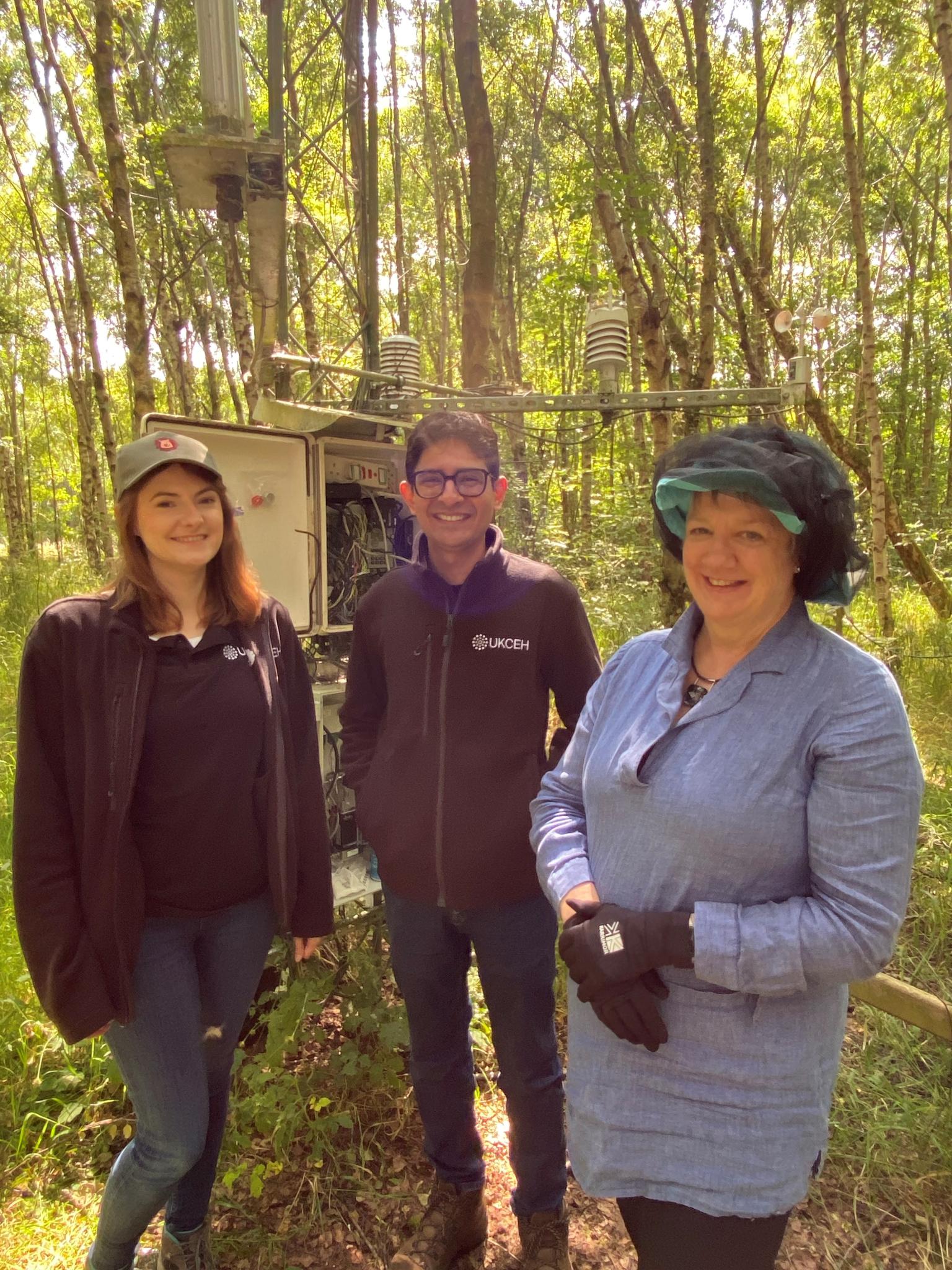 Three people stood in a woodland