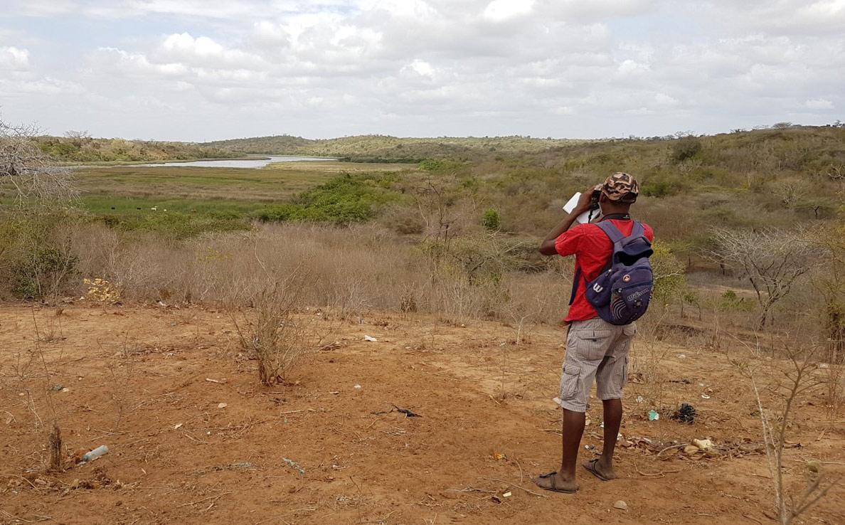 Man using binoculars to look across a Kenyan landscape