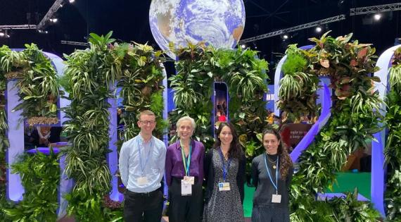 Four people standing under a representation of the earth