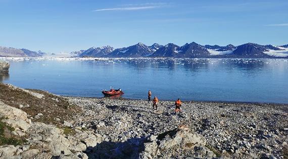 Three people and a boat standing beside a river in Svalbard