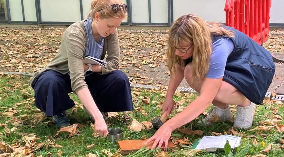 Two people crouching down looking at the ground