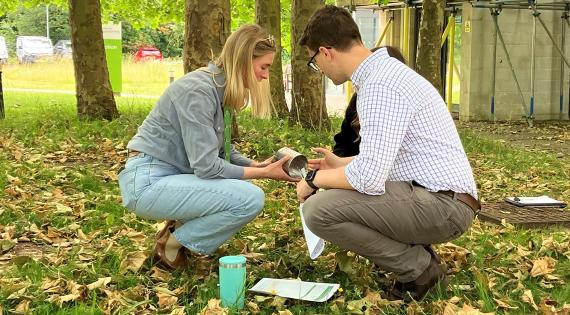 Two people crouched down checking soil infiltration