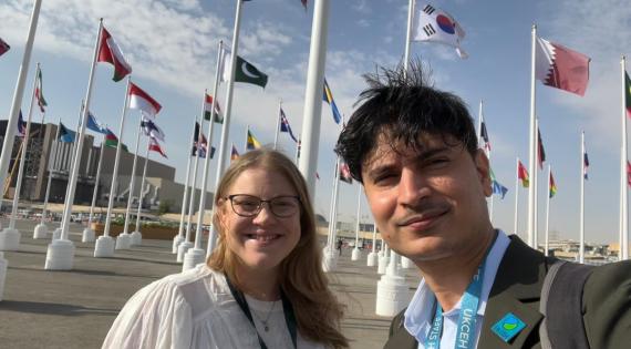 Lucy Barker and Srinidhi Jha with lots of flags behind at UNCCD COP16