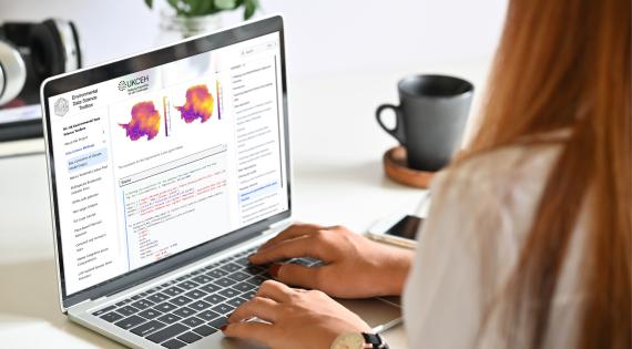 Woman with long hair on a laptop with images and text on the screen from the Environmental Data Science Toolbox