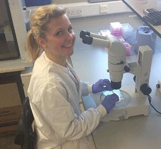 Woman in lab coat sitting at microscope