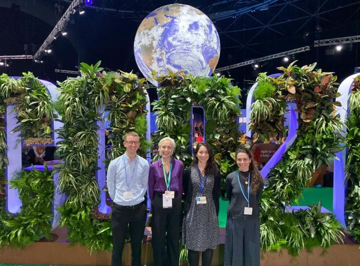 Four people standing under a representation of the earth