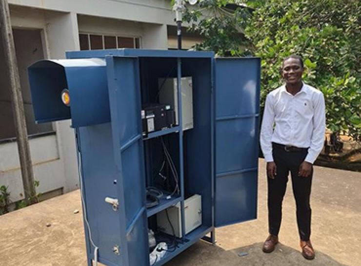 Dr Kofi Amegah standing beside the air pollution monitoring equipment