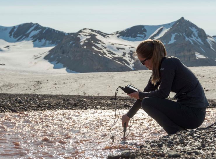 Alanna Grant probing water as it melts from the glacier in the background