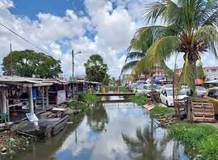 River in community in Guyana between buildings and road