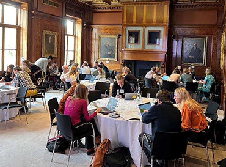 Workshop participants seated at different round tables in the Royal Society