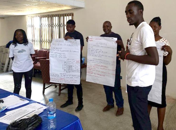 People holding flipchart pages in a small group