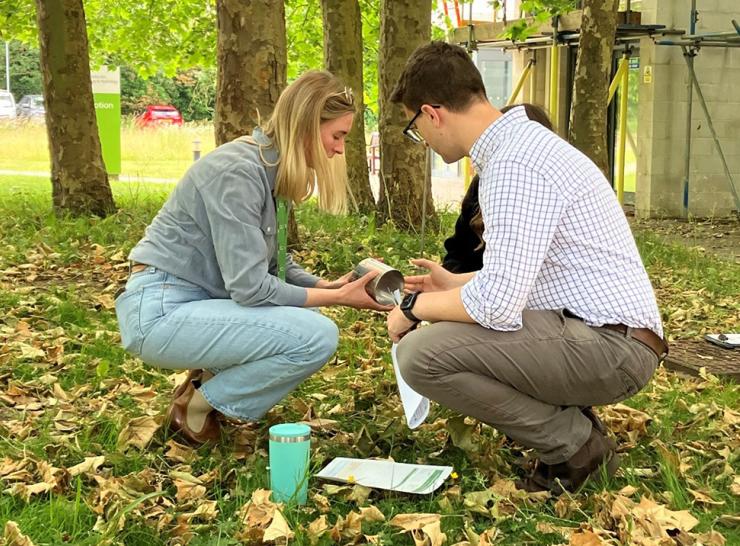 Two people crouched down checking soil infiltration