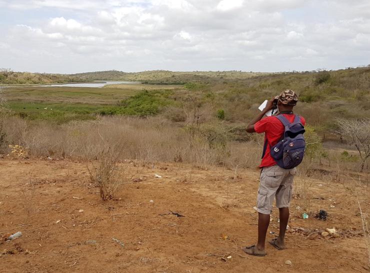 Man using binoculars to look across a Kenyan landscape